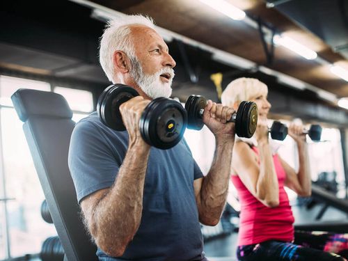 Älterer Mann und Frau trainieren die Schultern mit Kurzhanteln im Active Fitnessstudio in Bad Laasphe